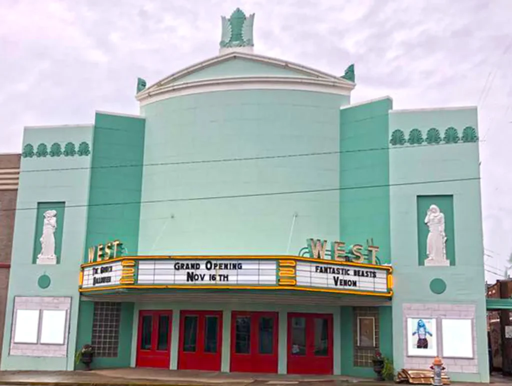 Art Deco-style Cedartown theater with mint green facade, red doors, and white statues. Marquee announces grand opening on Nov 16th, bringing films and life to the community.